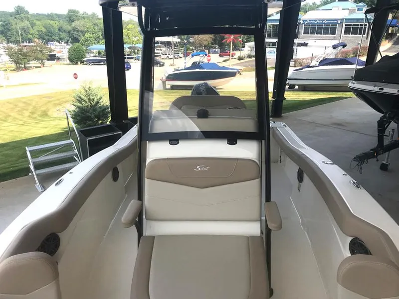 Slide: The Image of 2023 Scout 215 XSF boat interior with seating and console, docked at marina. - 9