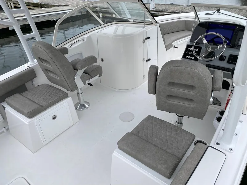 Slide: The Image of 2023 Sea Pro 240 DC boat interior with gray cushioned seats and modern dashboard. - 4