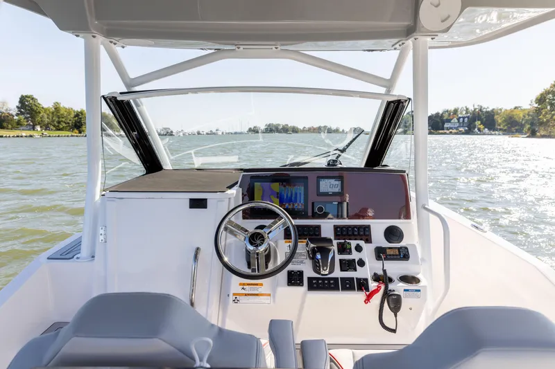 Slide: The Image of 2023 Solara S-250 CW boat cockpit with steering wheel and control panel on a lake. - 22