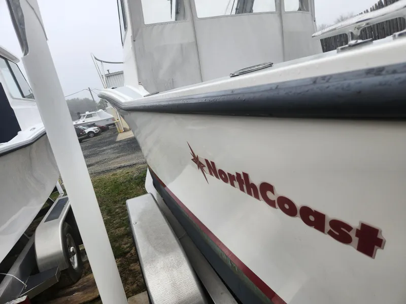 Slide: The Image of 2019 NorthCoast 215 HT boat, side view with logo, parked outdoors. - 17