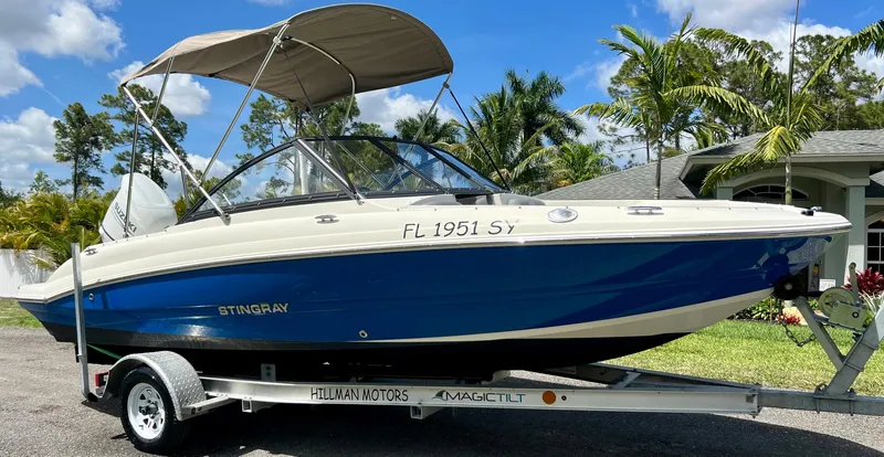 Slide: The Image of 2021 Stingray 191 DC boat on trailer with canopy, parked outdoors. - 12