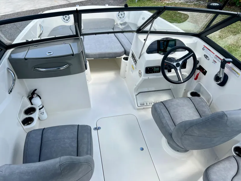 Slide: The Image of 2021 Stingray 191 DC boat interior with gray seating and modern dashboard. - 15