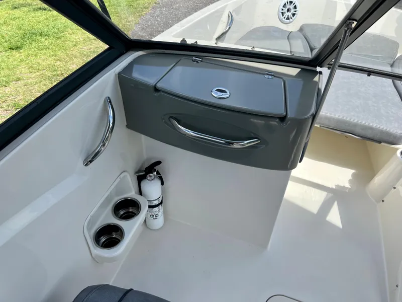Slide: The Image of 2021 Stingray 191 DC boat interior with storage compartment, cup holders, and fire extinguisher. - 18