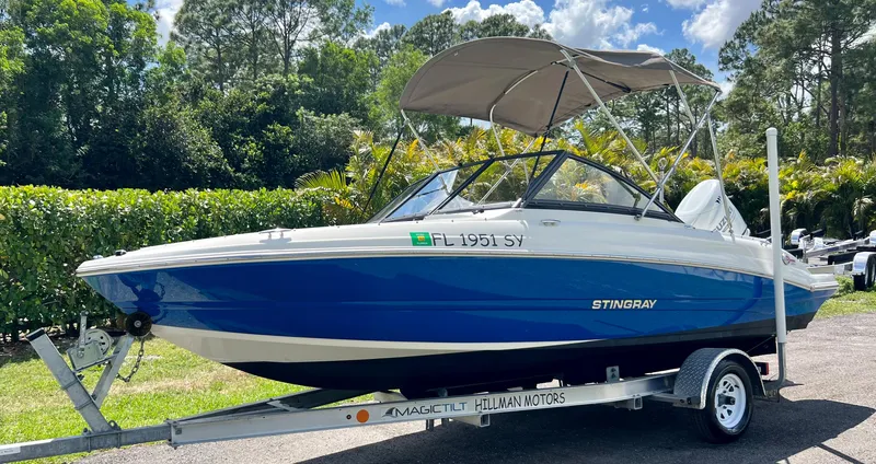 Slide: The Image of 2021 Stingray 191 DC boat on trailer with canopy, parked outdoors. - 3