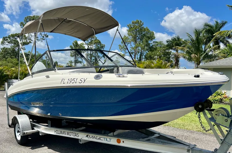 Slide: The Image of 2021 Stingray 191 DC boat on a trailer with a canopy, parked outdoors. - 5