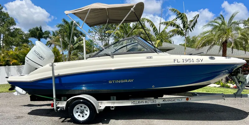 Slide: The Image of 2021 Stingray 191 DC boat on trailer with canopy, parked outdoors. - 6