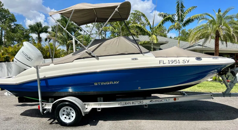 Slide: The Image of 2021 Stingray 191 DC boat on trailer with Suzuki outboard motor, parked outdoors. - 8