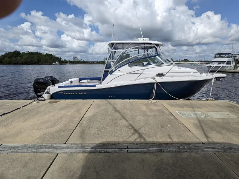Slide: The Image of 2008 Pro-Line 32 Express boat docked by a scenic waterfront under a cloudy sky. - 6