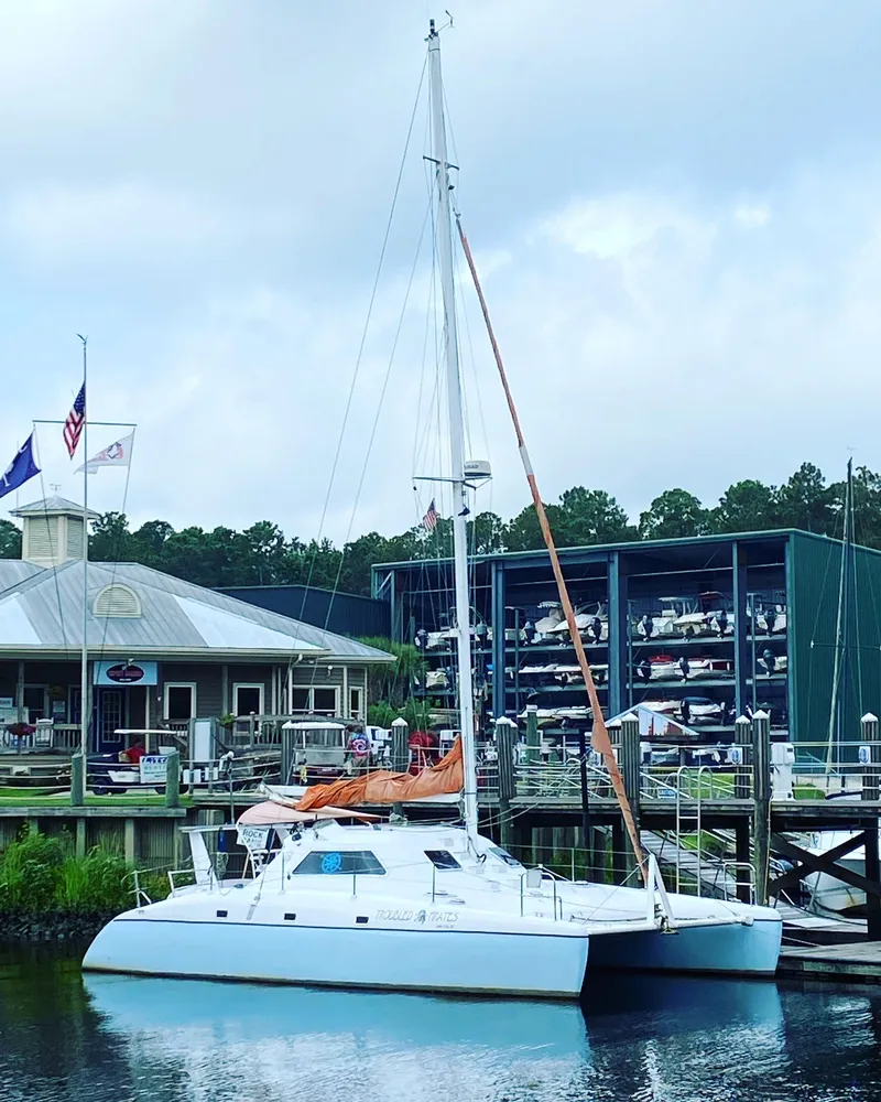 The Image of 1999 Wildcat 35 Catamaran docked at a marina with boat storage in the background. - 0