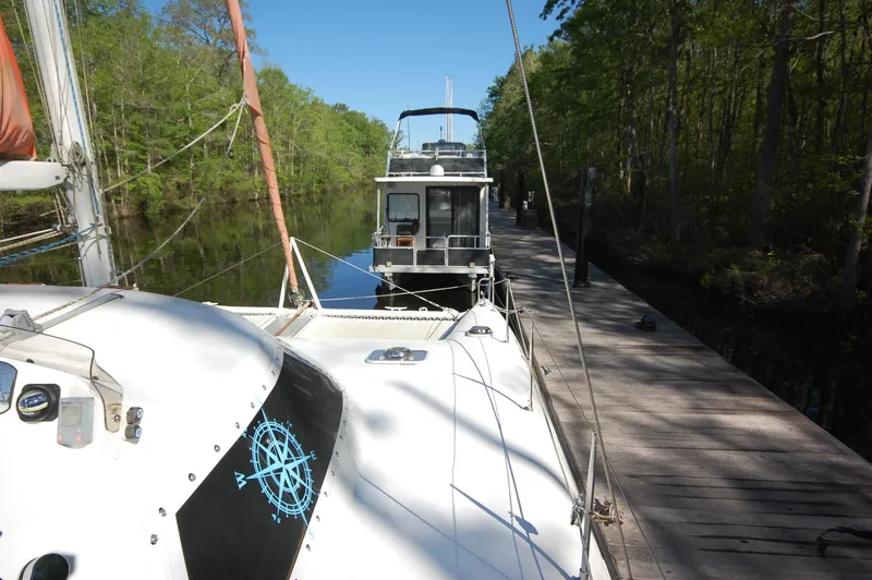 Slide: The Image of 1999 Wildcat 35 Catamaran docked beside a forested riverbank. - 10