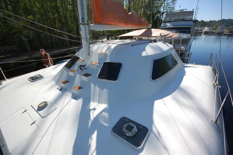 Slide: The Image of 1999 Wildcat 35 Catamaran with orange sail, docked in a marina. - 15