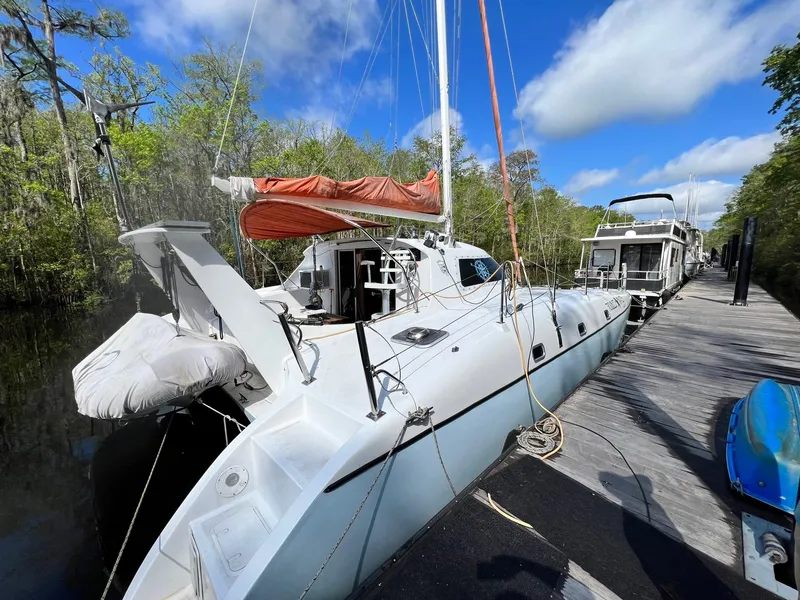 Slide: The Image of 1999 Wildcat 35 Catamaran docked by a scenic riverside. - 2