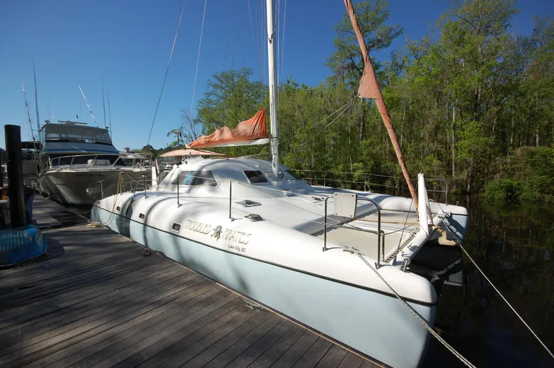 Slide: The Image of 1999 Wildcat 35 Catamaran docked near trees and other boats. - 3