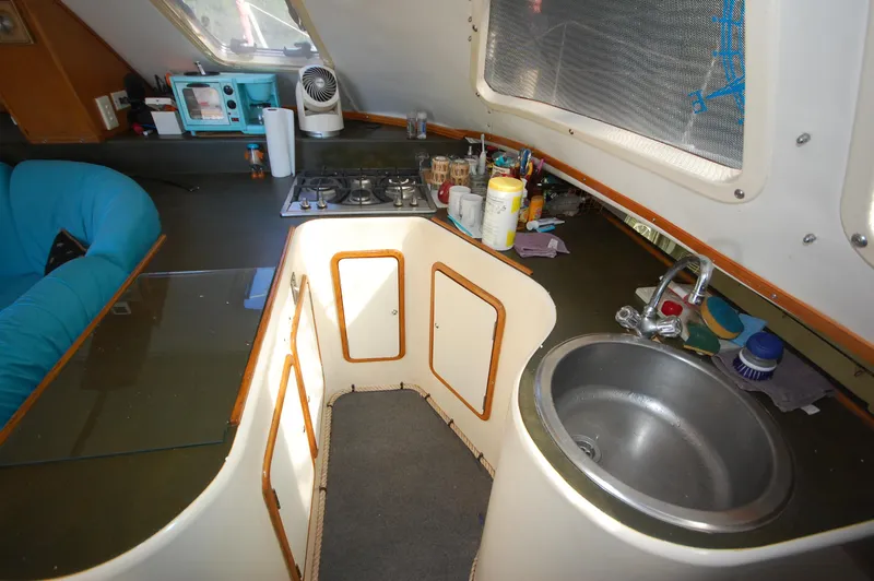 Slide: The Image of 1999 Wildcat 35 Catamaran kitchen with sink, stove, and seating area. - 33
