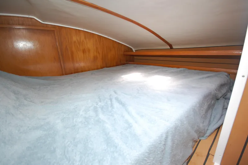 Slide: The Image of Cozy sleeping quarters in a 1999 Wildcat 35 Catamaran with wooden paneling. - 35