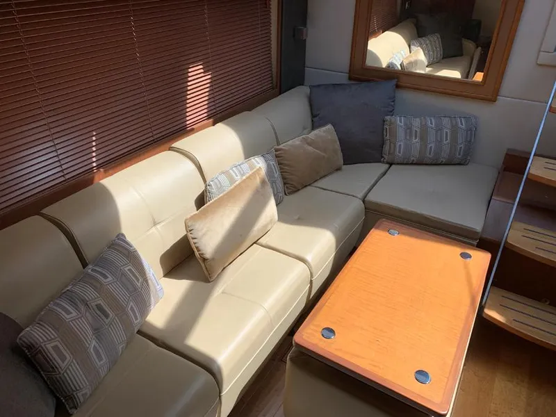Slide: The Image of Interior of 2014 Sea Ray 510 Sundancer with beige leather seating and wooden table. - 14