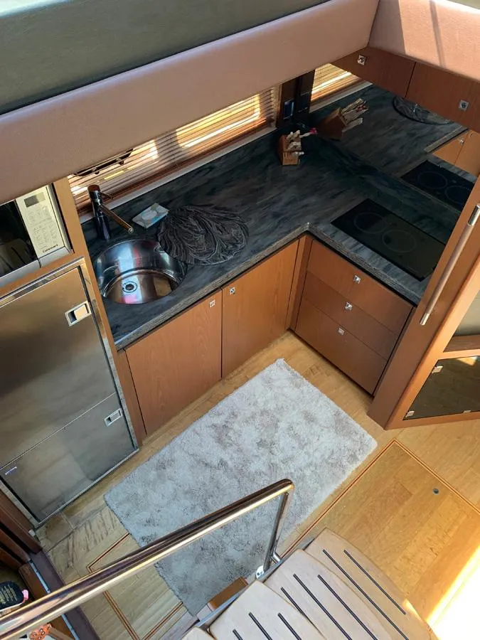 Slide: The Image of 2014 Sea Ray 510 Sundancer kitchen with stainless steel appliances and wooden cabinetry. - 25