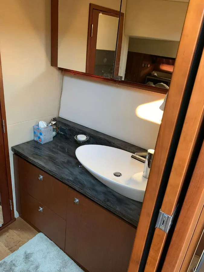 Slide: The Image of 2014 Sea Ray 510 Sundancer bathroom with modern sink and wooden cabinetry. - 28