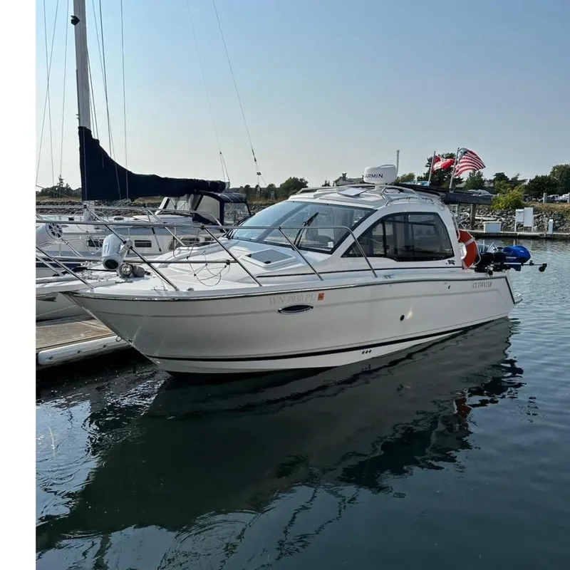 The Image of 2022 Cutwater C-24 Coupe boat docked in a marina, reflecting on calm water. - 0