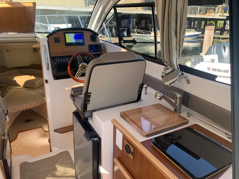 Slide: The Image of 2022 Cutwater C-24 Coupe interior with helm, kitchenette, and cozy cabin space. - 12