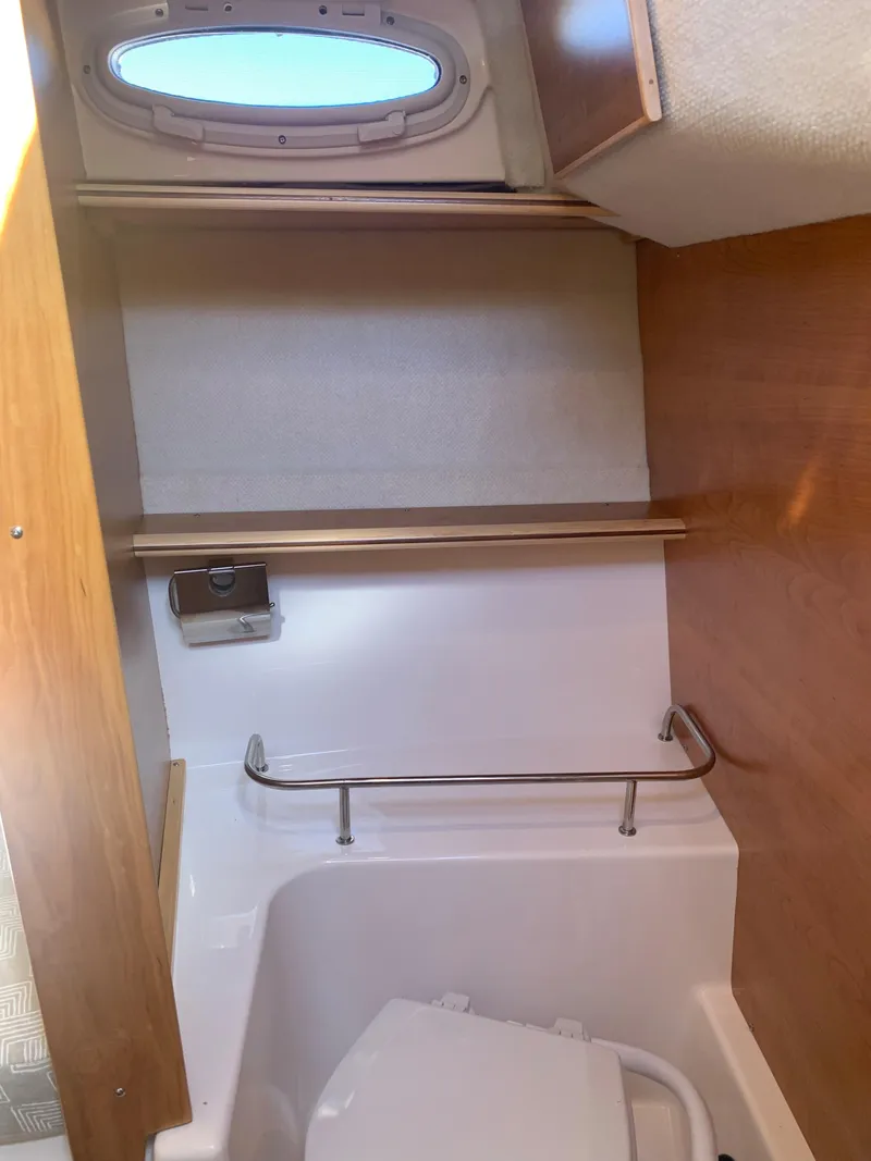 Slide: The Image of 2022 Cutwater C-24 Coupe boat interior bathroom with porthole and wooden accents. - 18