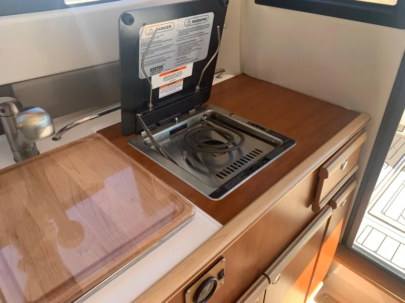 Slide: The Image of 2022 Cutwater C-24 Coupe interior kitchen with stove and wooden countertop. - 20