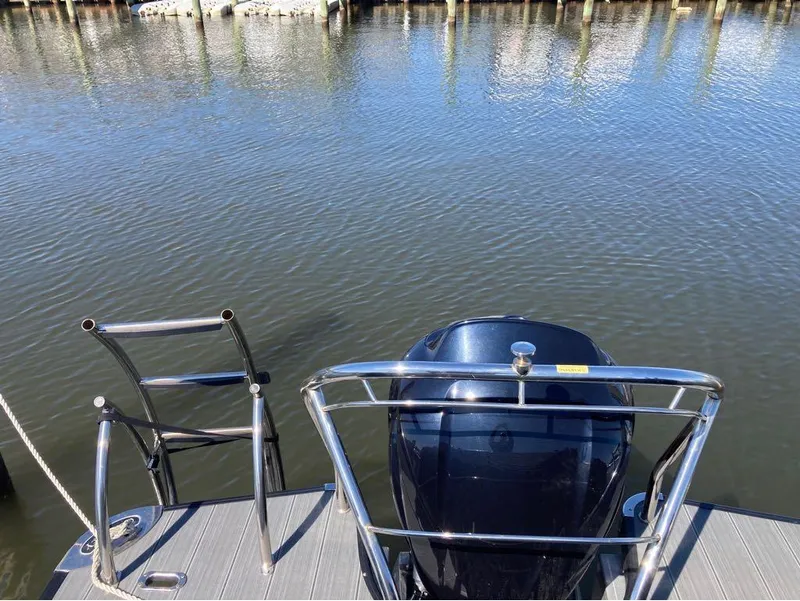 Slide: The Image of Godfrey San Pan 26 boat (2020) with outboard motor, docked on calm water. - 14