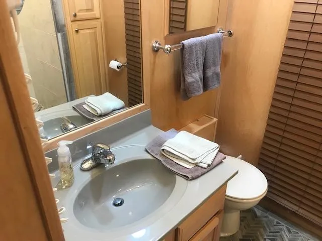 Slide: The Image of 2002 Sumerset Houseboat bathroom with sink, mirror, towels, and wooden cabinets. - 19