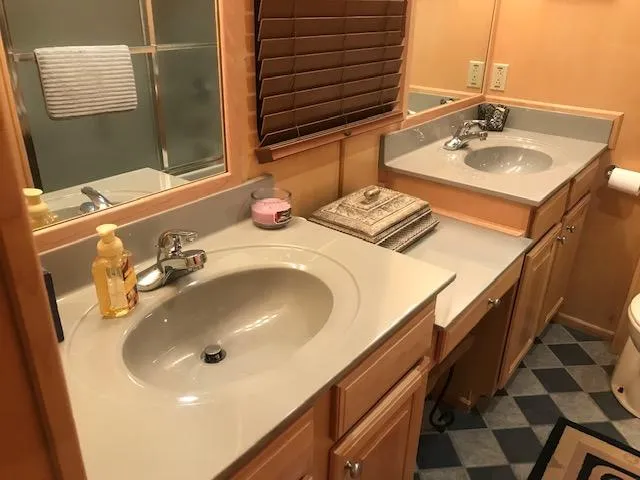 Slide: The Image of 2002 Sumerset Houseboat bathroom with dual sinks, wooden cabinets, and a large mirror. - 21