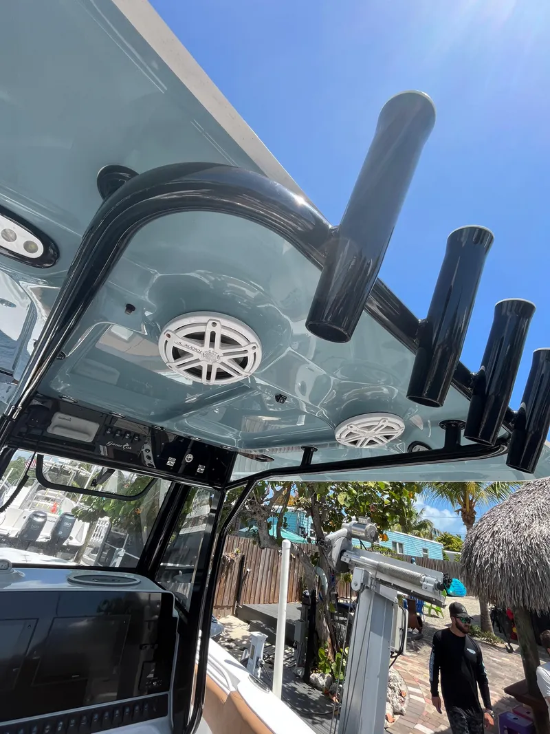 Slide: The Image of 2020 Sea Hunt 30 Gamefish boat interior with rod holders and speakers under a clear blue sky. - 13