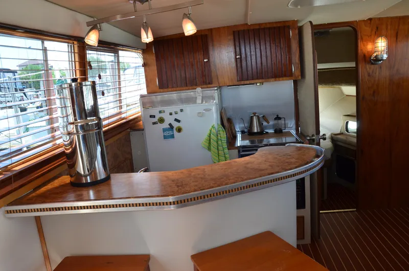 Slide: The Image of 1984 Chris-Craft 381 Catalina yacht interior with kitchen, wooden cabinets, and bar counter. - 21