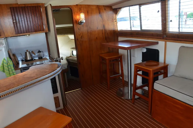Slide: The Image of 1984 Chris-Craft 381 Catalina interior with wood accents, kitchenette, and seating area. - 22