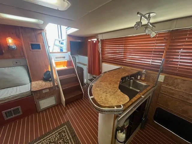 Slide: The Image of 1984 Chris-Craft 381 Catalina interior with wood accents, kitchenette, and stairs. - 26