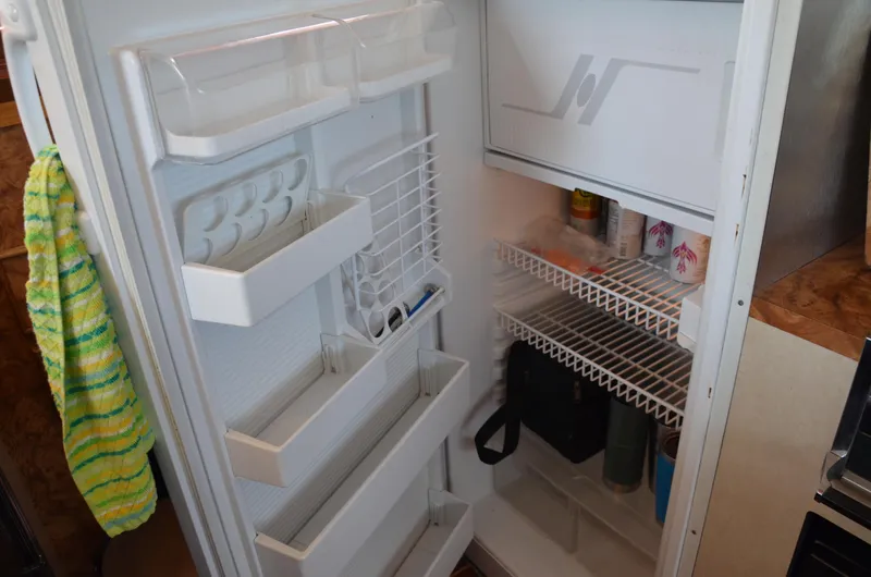 Slide: The Image of Open refrigerator inside 1984 Chris-Craft 381 Catalina boat, showing shelves and door storage. - 29