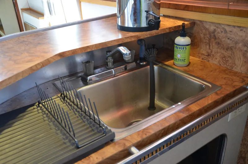 Slide: The Image of 1984 Chris-Craft 381 Catalina kitchen sink with wooden countertop and dish rack. - 30