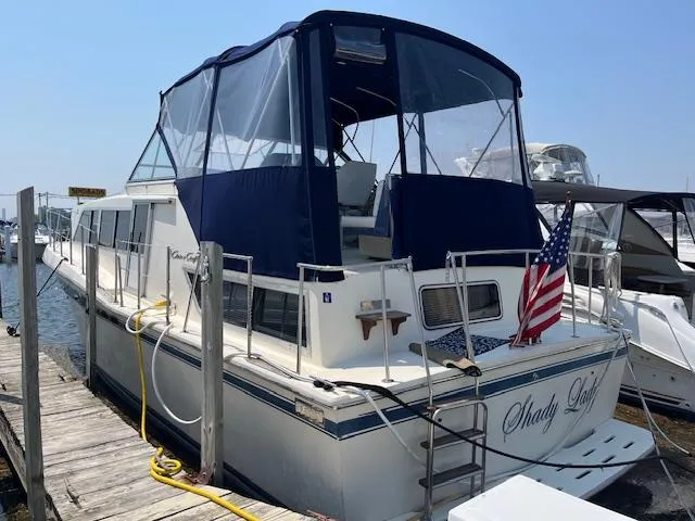 Slide: The Image of 1984 Chris-Craft 381 Catalina docked, featuring blue canopy and American flag. - 49