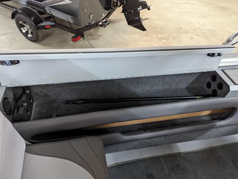 Slide: The Image of 2023 Smoker Craft Pro Angler XL 182 storage compartment with rod holder and trailer in background. - 9