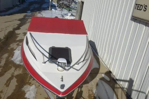 Slide: The Image of 1990 Sunbird CORSICA 188 Cuddy Cabin boat with red and white exterior, docked near a building. - 17