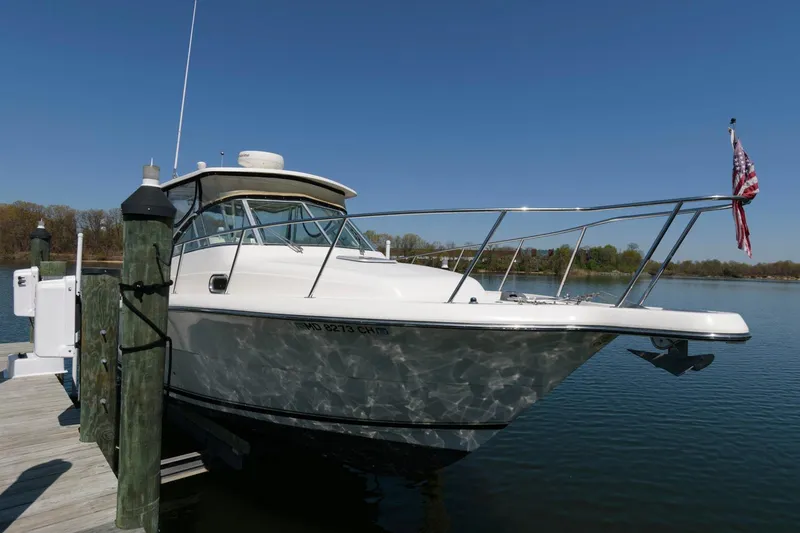 Slide: The Image of 2006 Pursuit 3070 Offshore boat docked at a marina on a sunny day. - 2