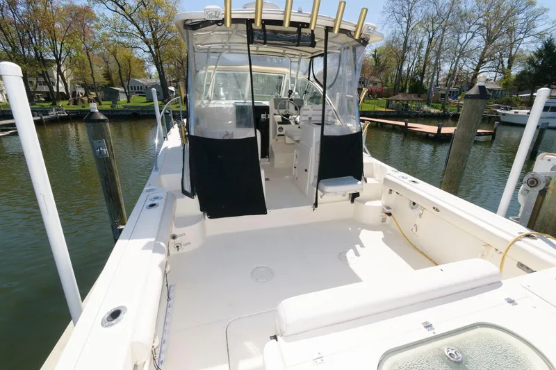 Slide: The Image of 2006 Pursuit 3070 Offshore boat docked, spacious deck, clear canopy, and fishing rod holders. - 3