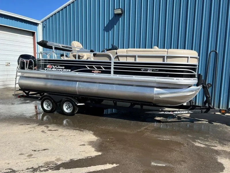 The Image of 2023 Sun Tracker Sportfish™ 20 DLX pontoon boat on trailer outside blue building. - 0