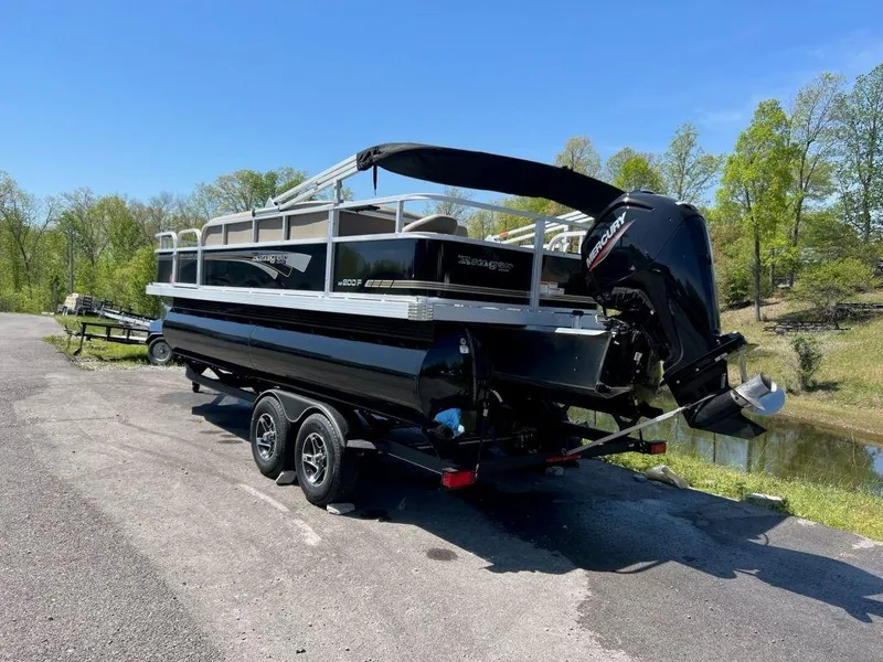 Slide: The Image of 2023 Ranger 200F pontoon boat on a trailer by a lake. - 6