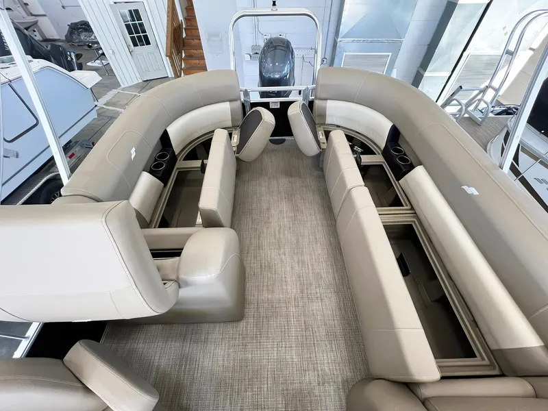 Slide: The Image of 2023 Starcraft LX 22 R pontoon boat interior with beige seating and carpeted floor. - 19