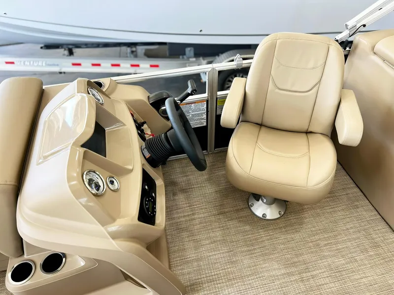 Slide: The Image of 2023 Starcraft LX 22 R boat interior with beige captain's chair and control panel. - 2