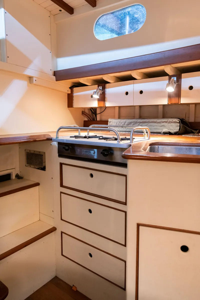 Slide: The Image of Cozy interior of 2008 Custom Frank Paine Sloop with compact kitchen and wooden accents. - 32