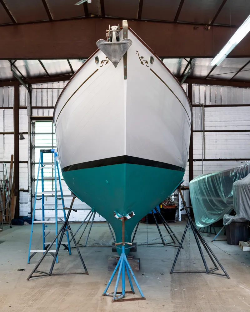 Slide: The Image of Custom 2008 Frank Paine Sloop in a workshop, supported by stands, with a blue ladder nearby. - 9