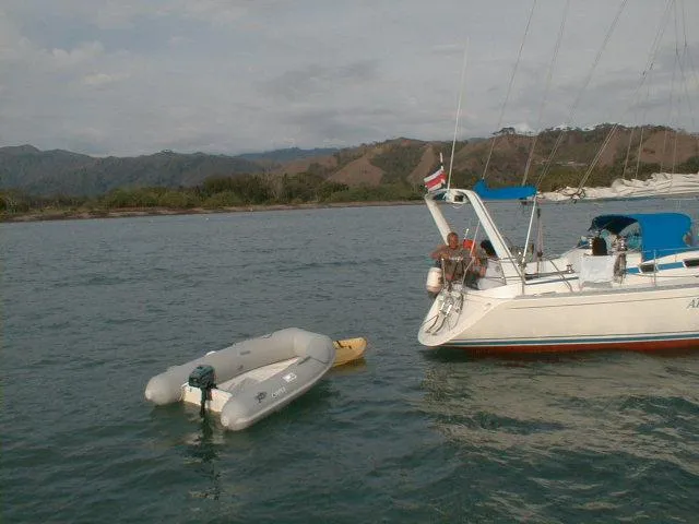 Slide: The Image of Sailboat with Apex A 10 Lite dinghy anchored near a scenic coastline, 2022 model. - 2