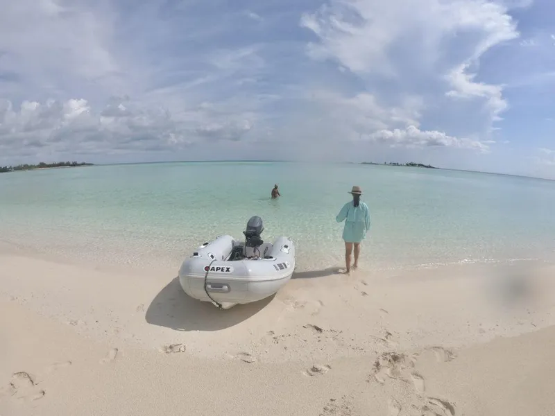 Slide: The Image of 2022 Apex A10 RIB on a pristine beach with clear turquoise water and people enjoying the view. - 4