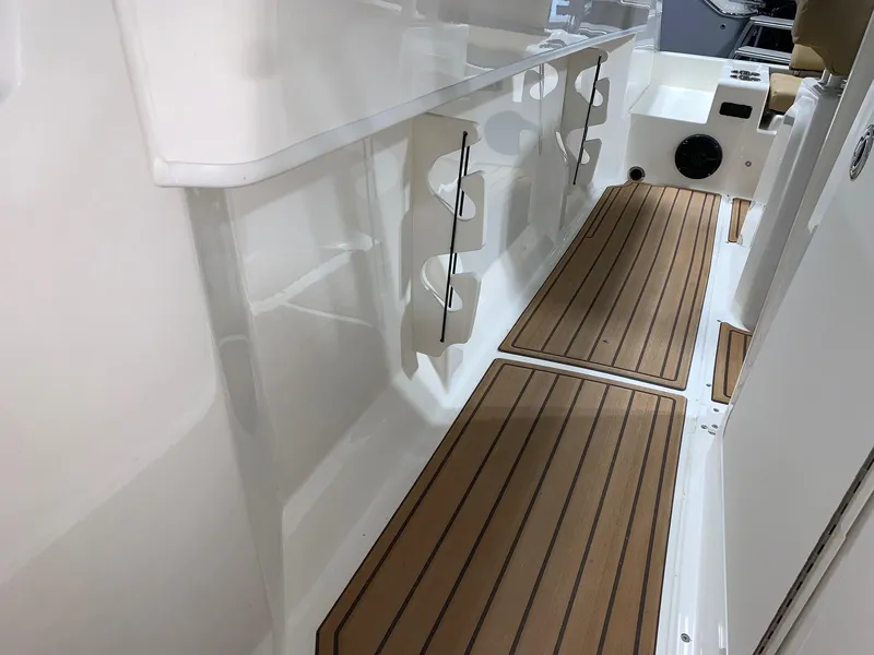 Slide: The Image of 2024 Bayliner Trophy 22CC interior with rod holders and teak-style flooring. - 11