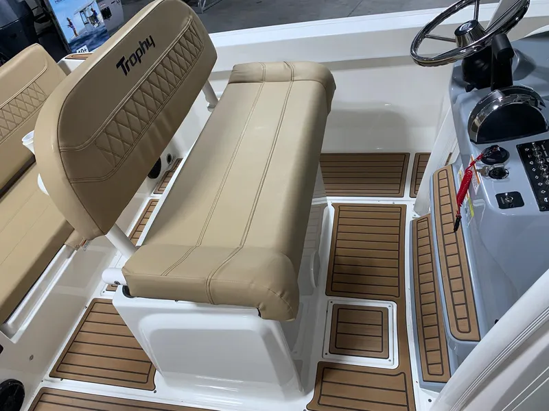 Slide: The Image of 2024 Bayliner Trophy 22CC boat interior with tan seating and wood-patterned flooring. - 13